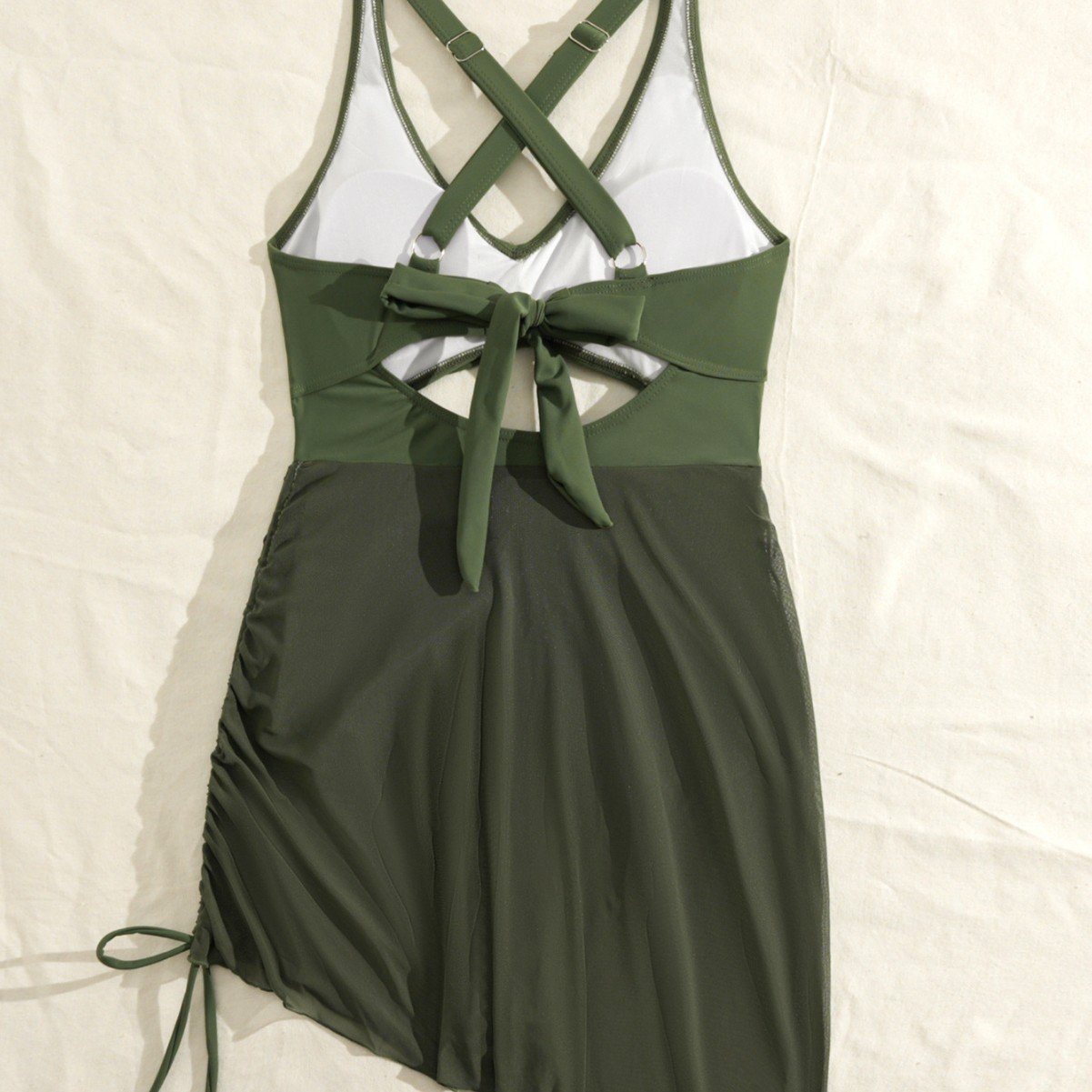 Green one-piece swimsuit with crisscross back straps, tie-front cutout, and sheer wrap skirt.