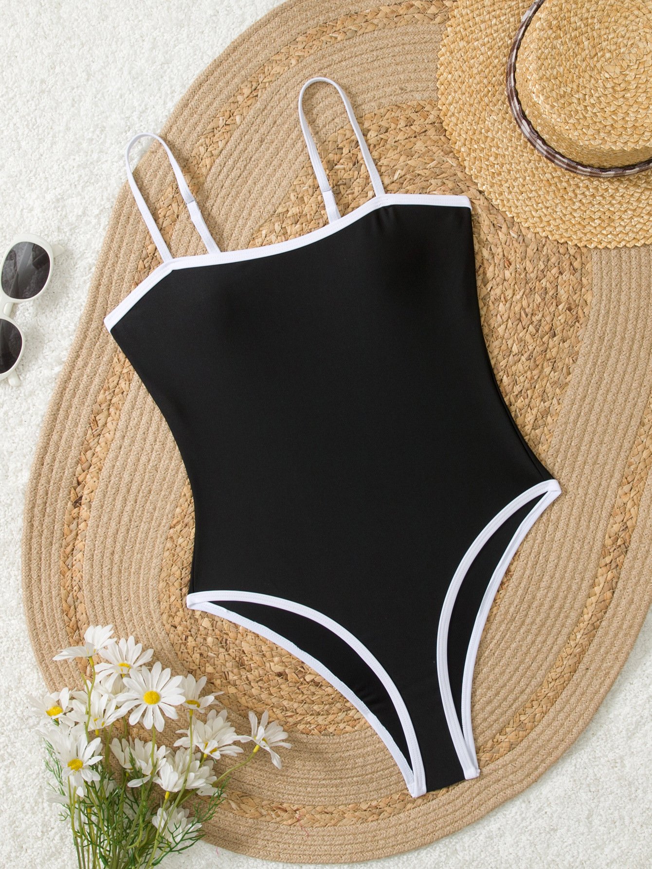 Black one-piece swimsuit with white piping, square neckline, and thin straps.