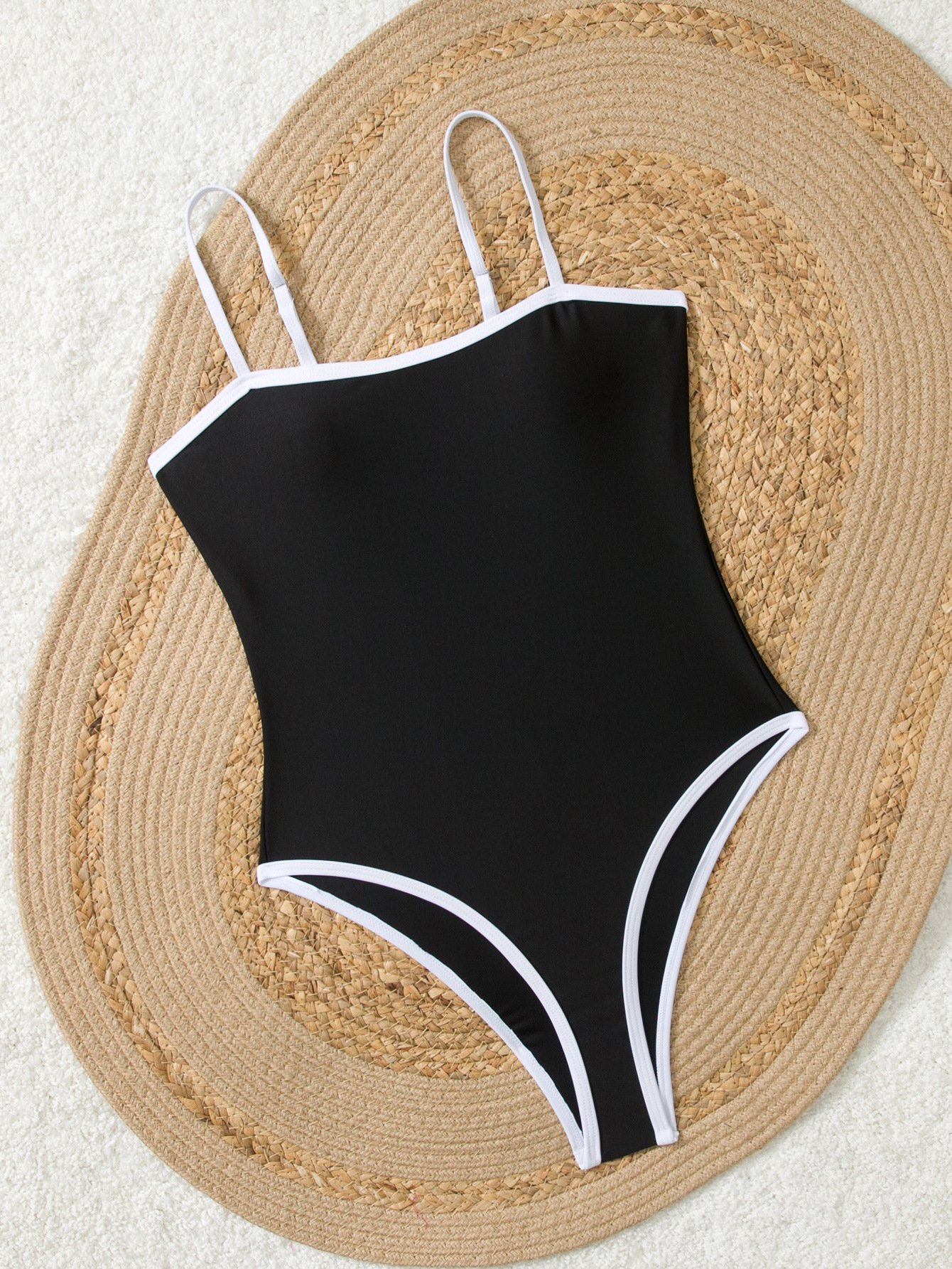 Black one-piece swimsuit with white piping, square neckline, and thin straps.