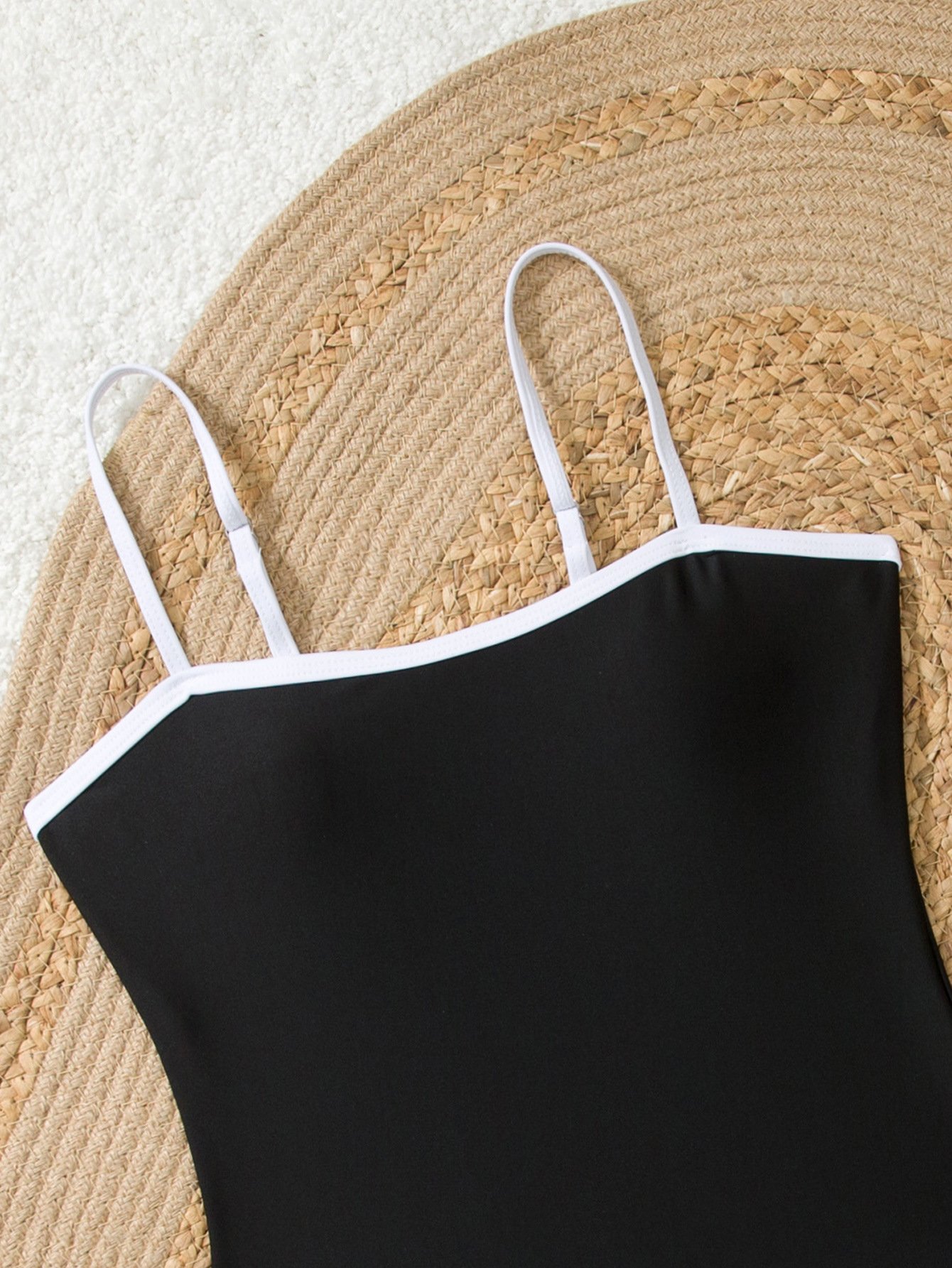 Black one-piece swimsuit featuring white piping, a square neckline, and thin adjustable straps.