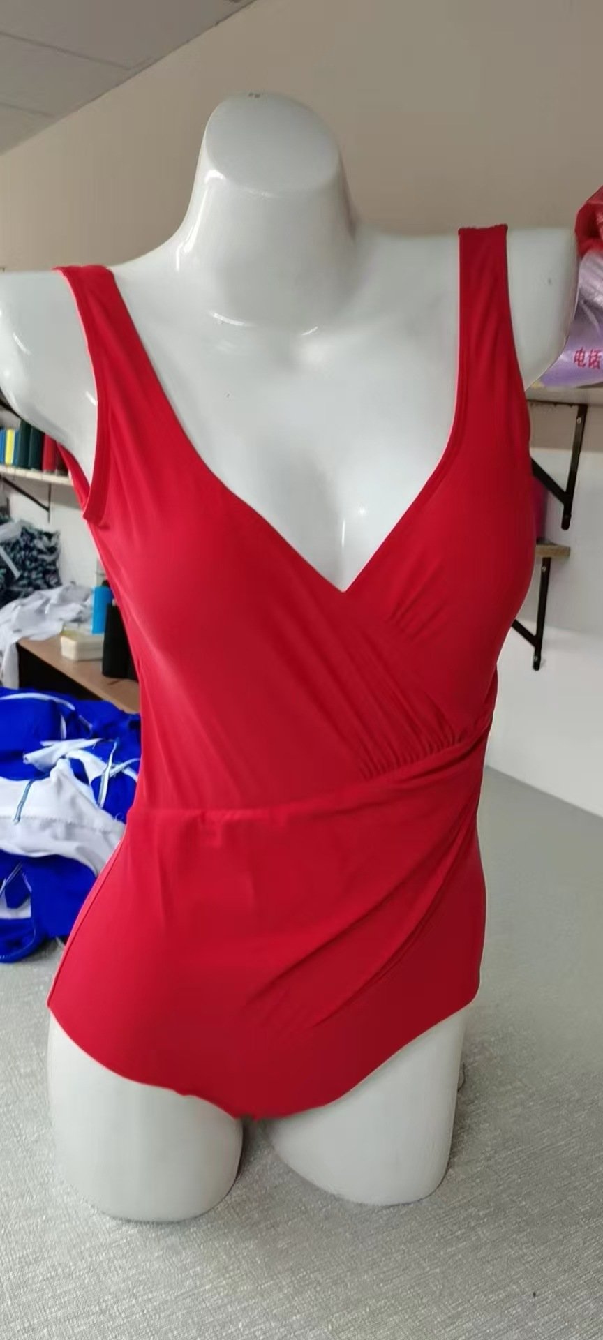 Red one-piece swimsuit featuring a deep V-neckline, wrap-front bodice, and wide shoulder straps.