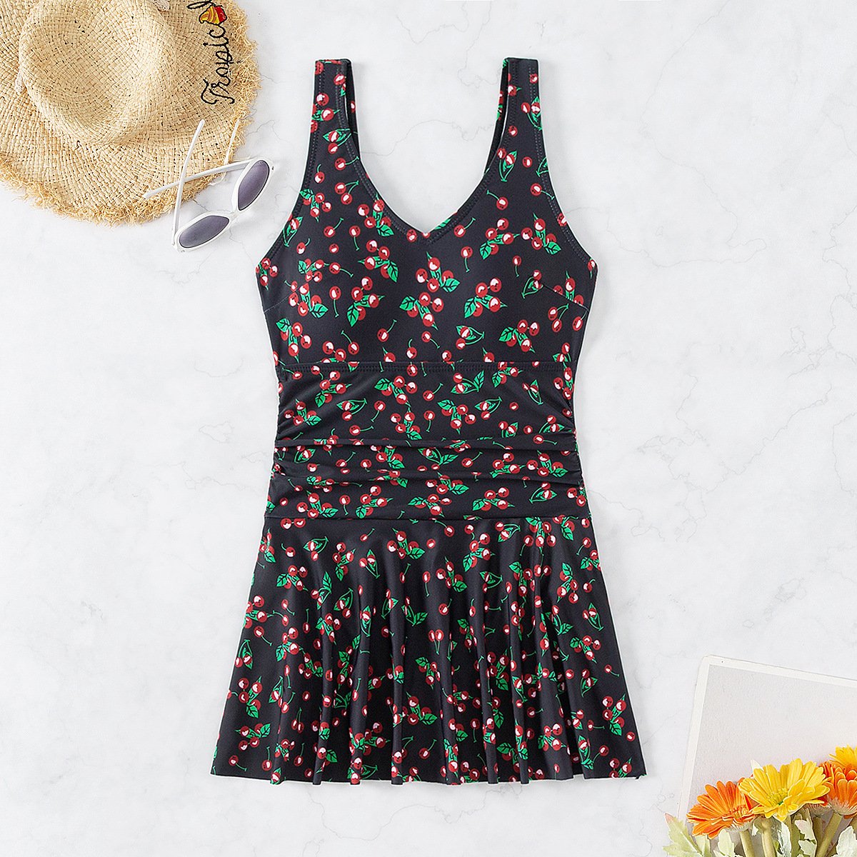 Black cherry print sleeveless V-neck one-piece swimsuit with a flared skirt overlay.