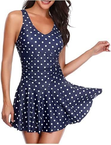 Navy blue one-piece swimsuit with white polka dots, featuring a V-neckline and a flared skirt overlay.