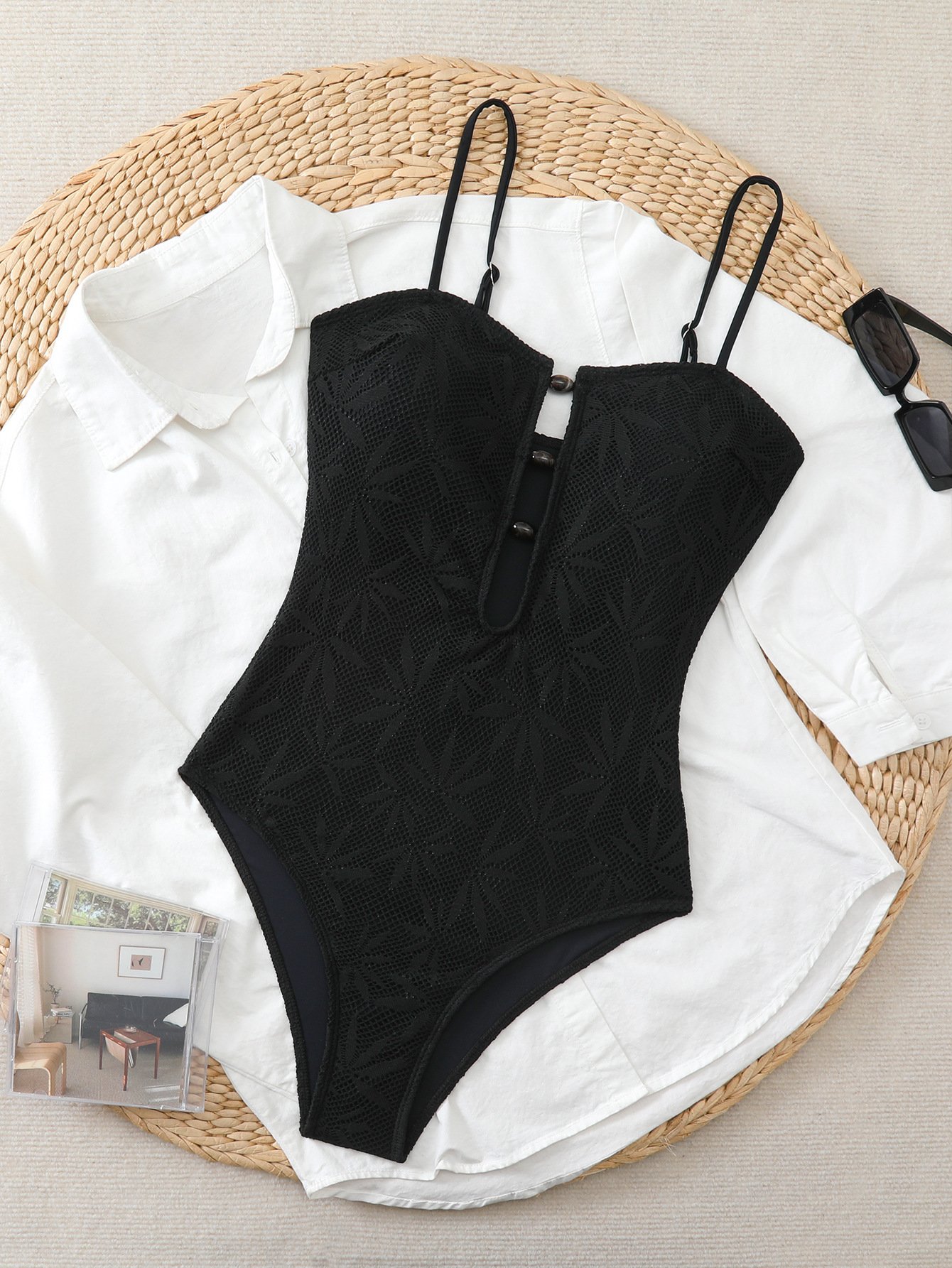 Black textured one-piece swimsuit featuring adjustable spaghetti straps, button front closure, and high-cut legs.