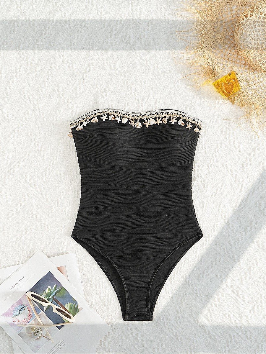 Black strapless one-piece swimsuit featuring horizontal ruching and a decorative seashell-trimmed neckline.