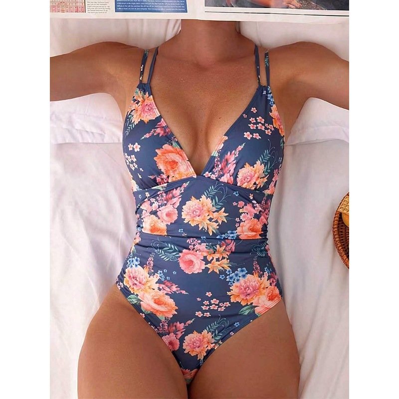 A navy blue floral print one-piece swimsuit with a deep V-neckline and double spaghetti straps.