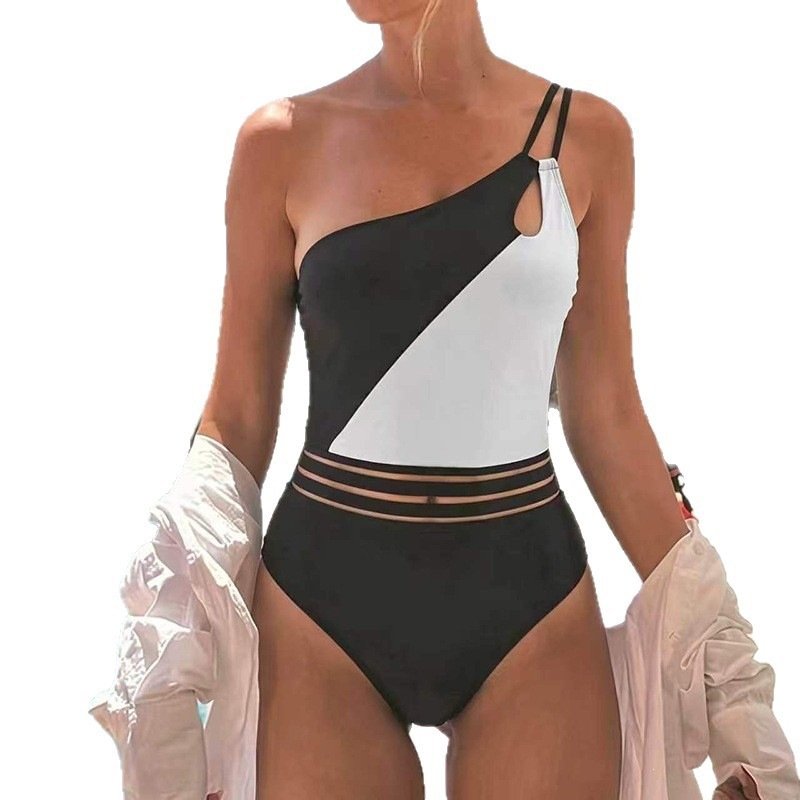 Black and white one-shoulder one-piece swimsuit with diagonal color block, chest cutout, and strappy waist details.