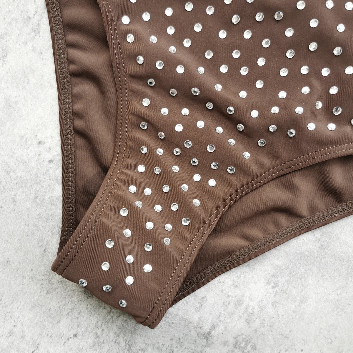 Close-up of a brown embellished monokini featuring rhinestone details on the high-cut leg.