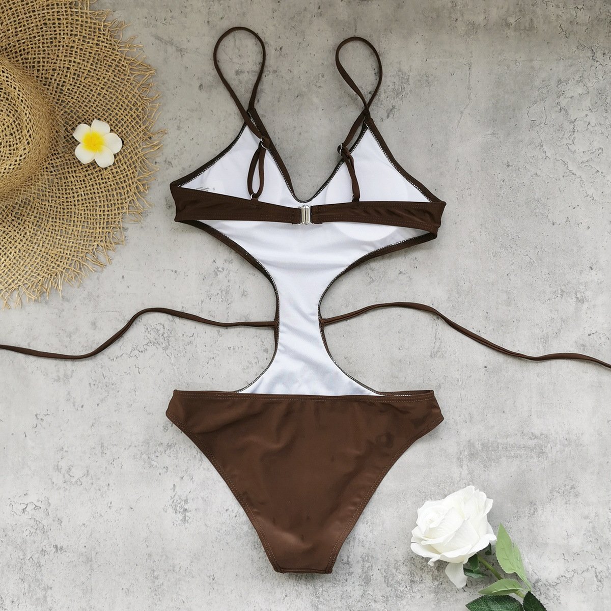 White and brown cutout one-piece swimsuit with adjustable spaghetti straps and side ties.
