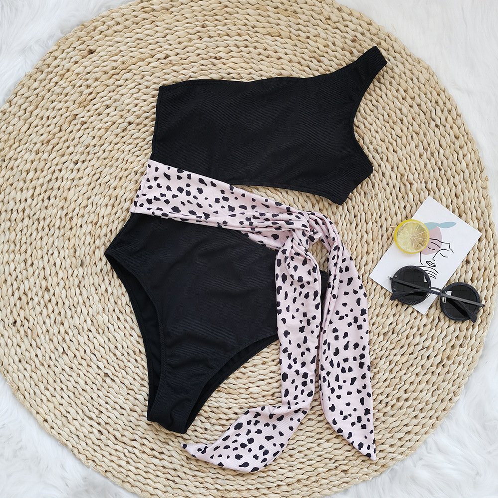 Black one-piece swimsuit with one-shoulder neckline, side cutout, and leopard print tie belt.