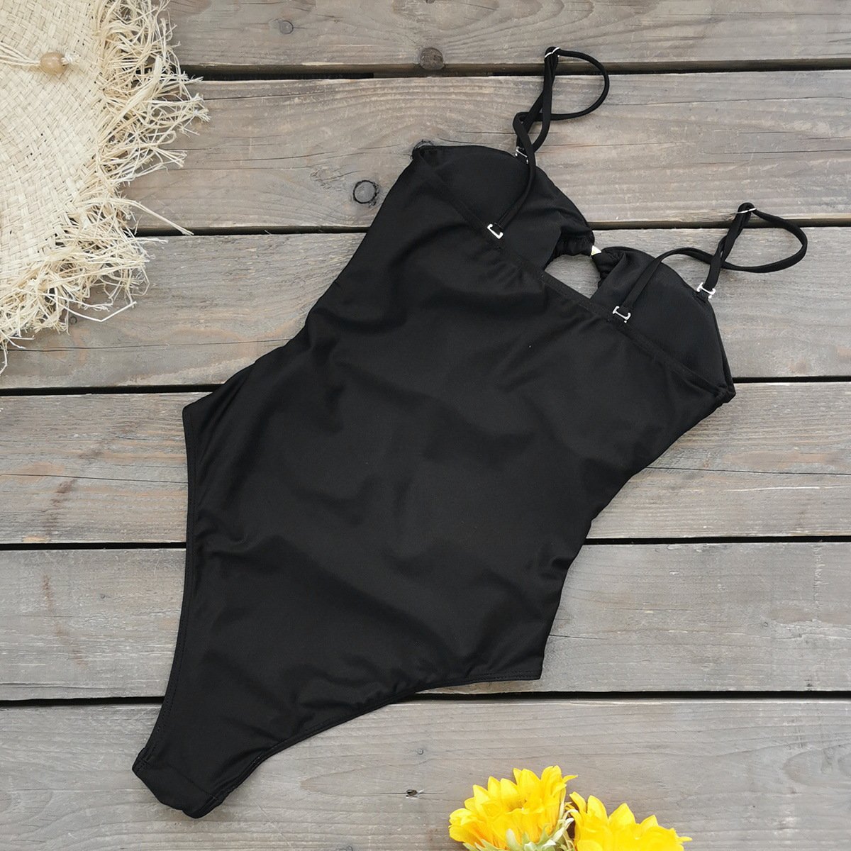 Black one-piece swimsuit with thin adjustable straps, cutout back detail, and high-cut legs.
