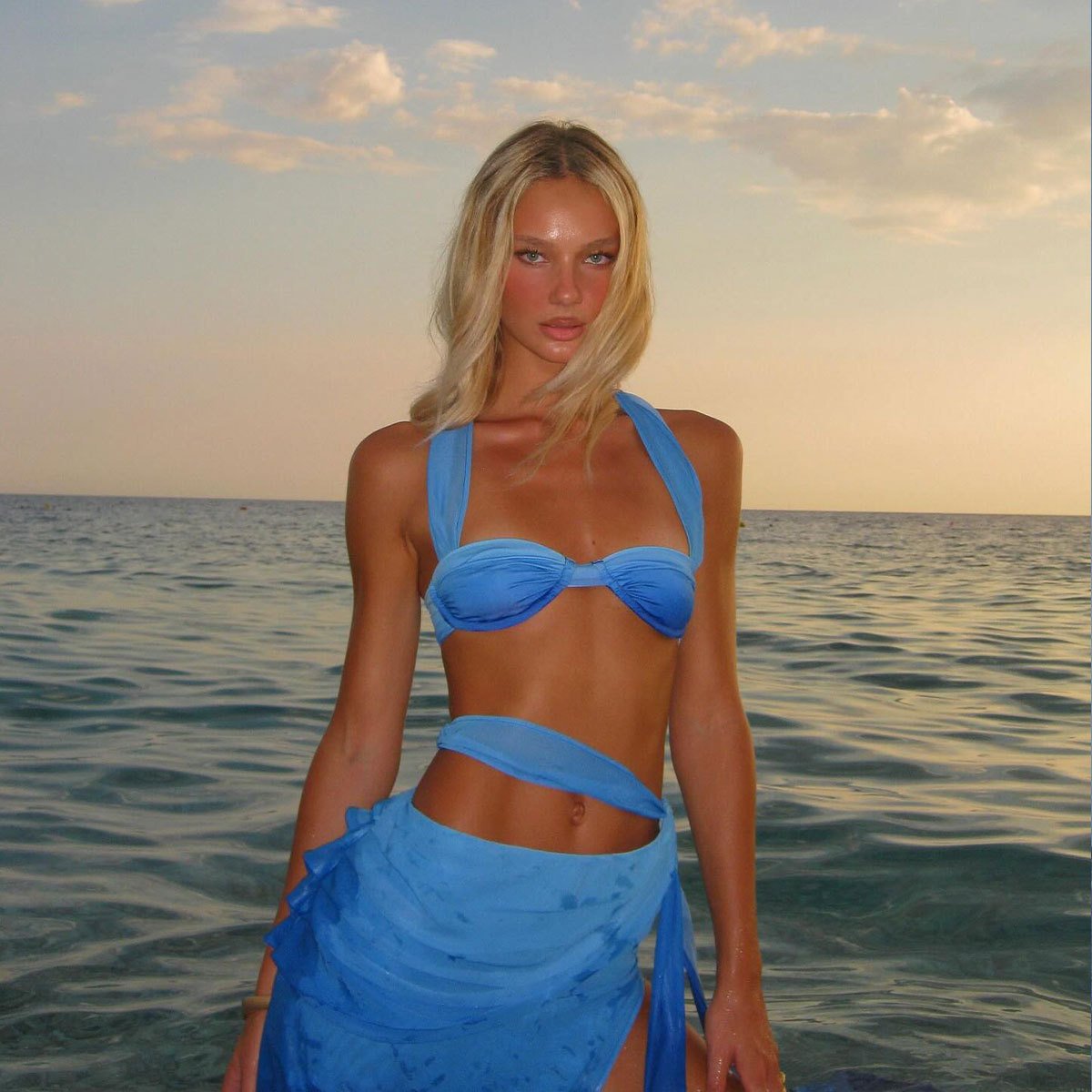 Blue halter bikini top with gathered cups paired with a matching wrap skirt featuring a high slit.