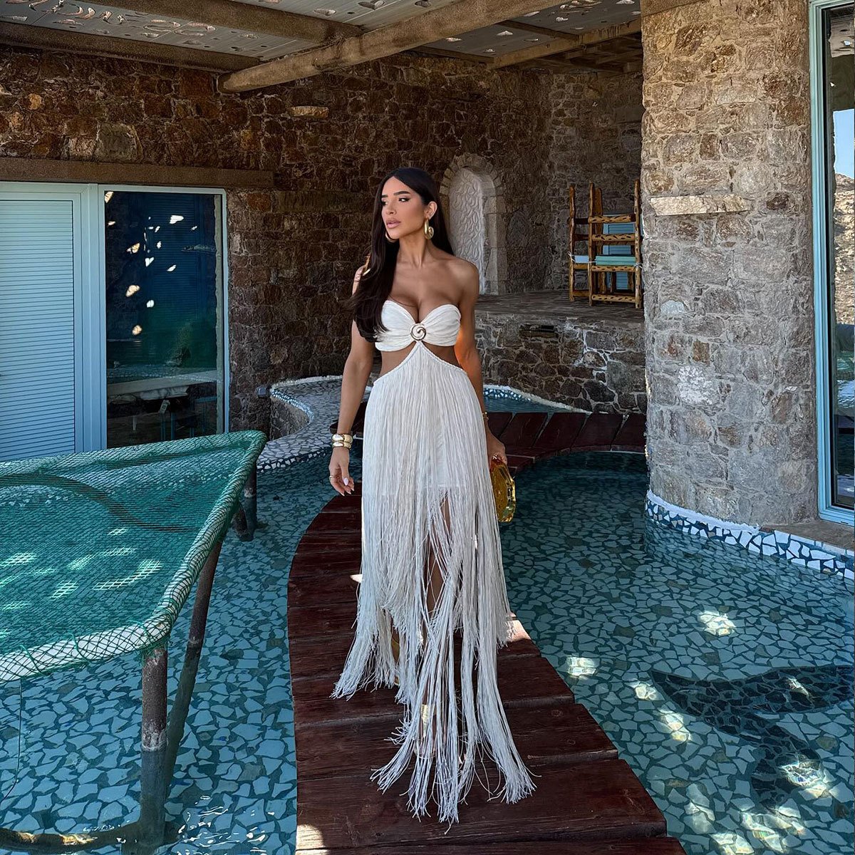 White strapless one-piece swimsuit with a central ring cutout and long tiered fringe skirt.