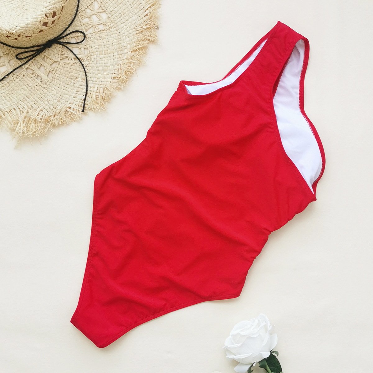 Red one-shoulder one-piece swimsuit with asymmetrical neckline and white inner lining.