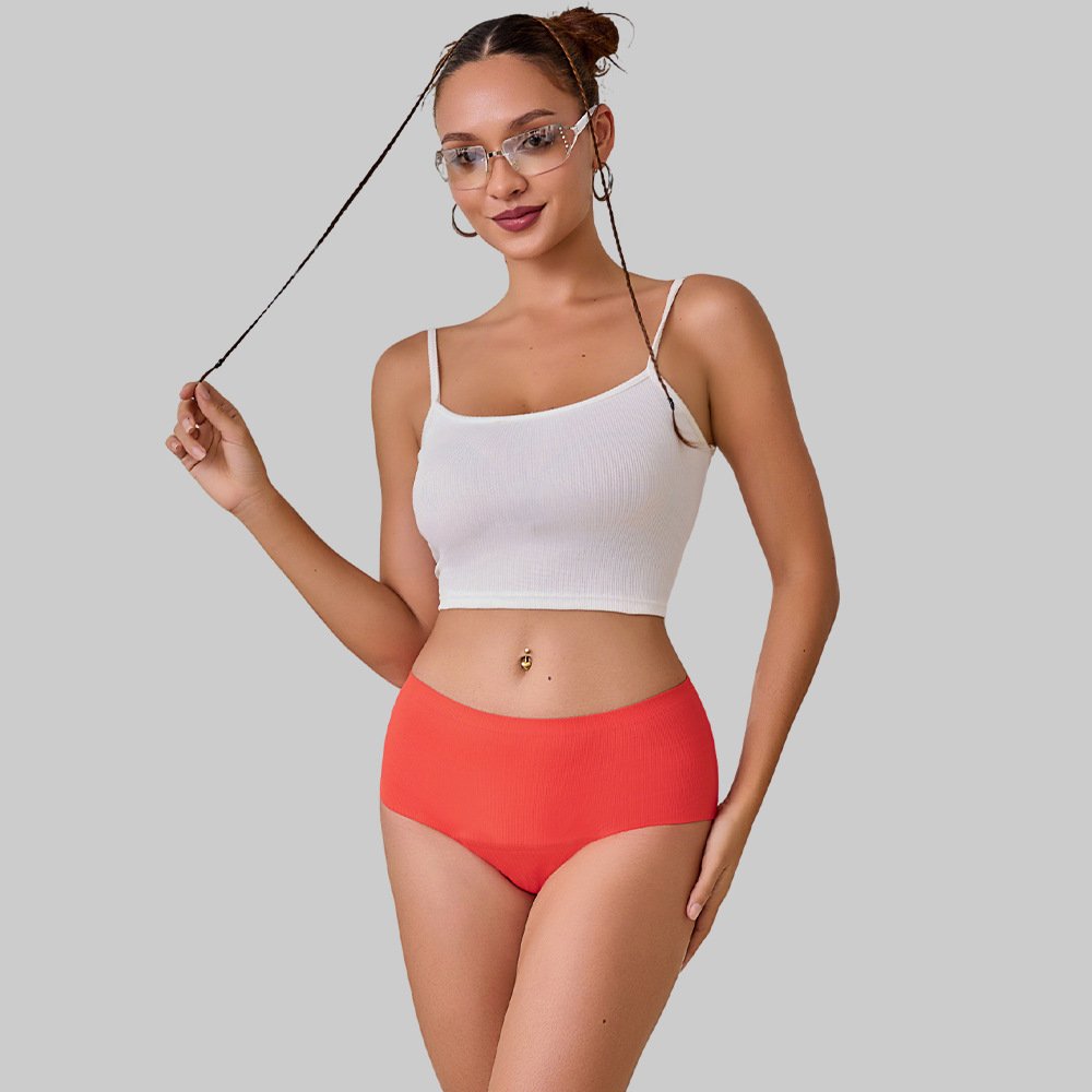 Model wearing coral high-waisted period swim briefs with a wide elastic waistband and full coverage.
