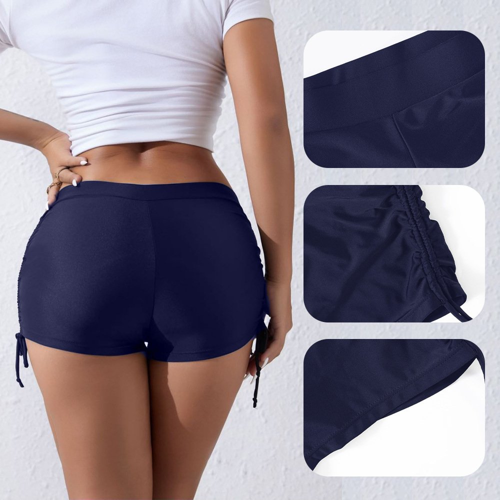 Navy blue high-waisted swim shorts featuring ruched side ties and a wide elastic waistband.