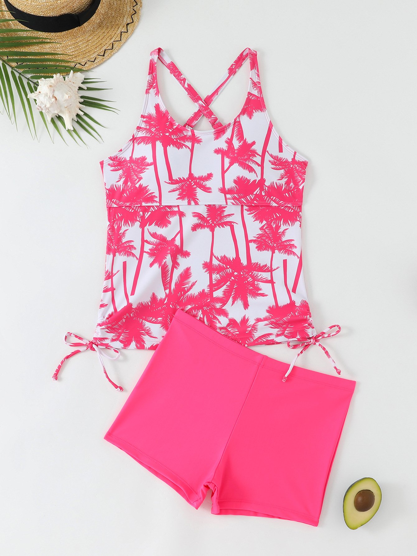 A two-piece swim set featuring a white tankini top with pink palm tree print, crossback straps, and side