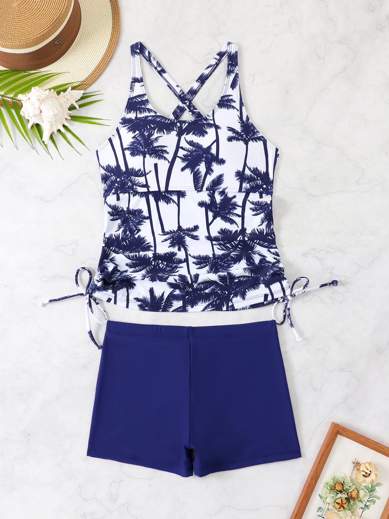 Blue and white palm print tankini with crossback straps and side ties, paired with solid blue boyshort bottoms.