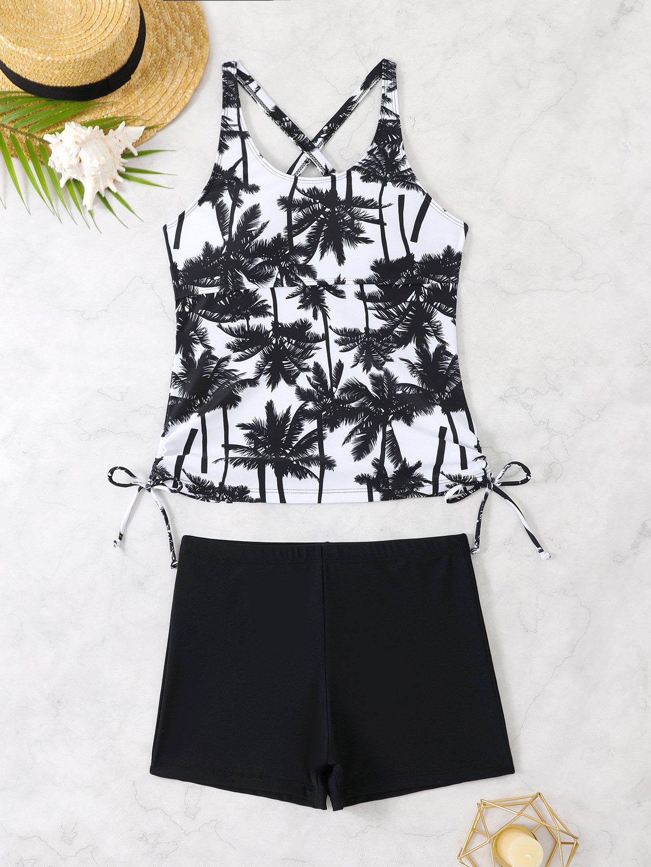 Black and white palm print tankini set with crossback straps, side tie details, and solid black boyshort bottoms.