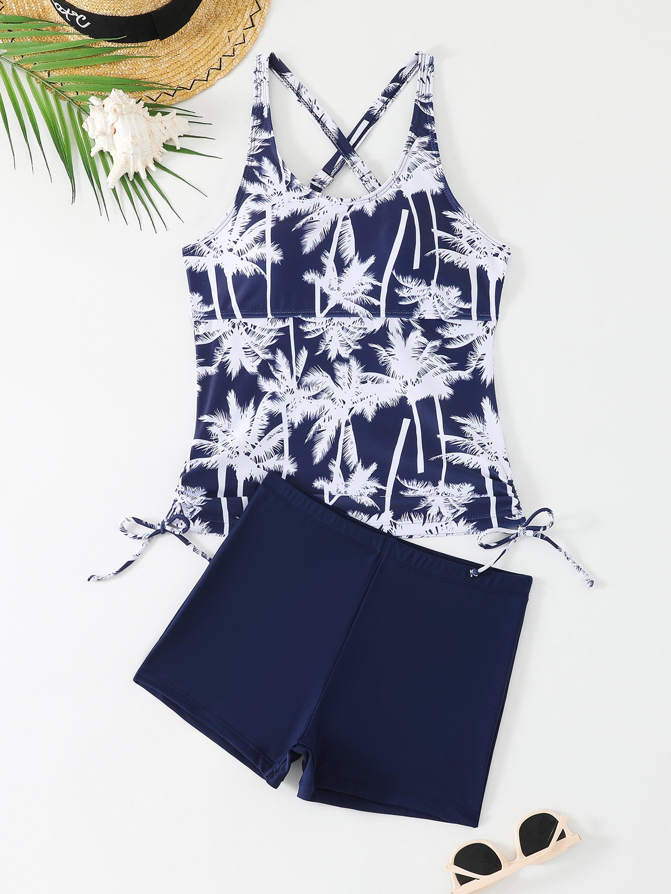Navy blue and white palm print tankini top with crossback straps and side ties, paired with solid navy