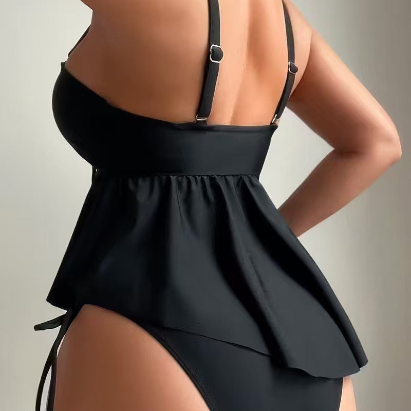 Black one-piece swimsuit featuring adjustable straps, a gathered bust, and a flared peplum skirt overlay.